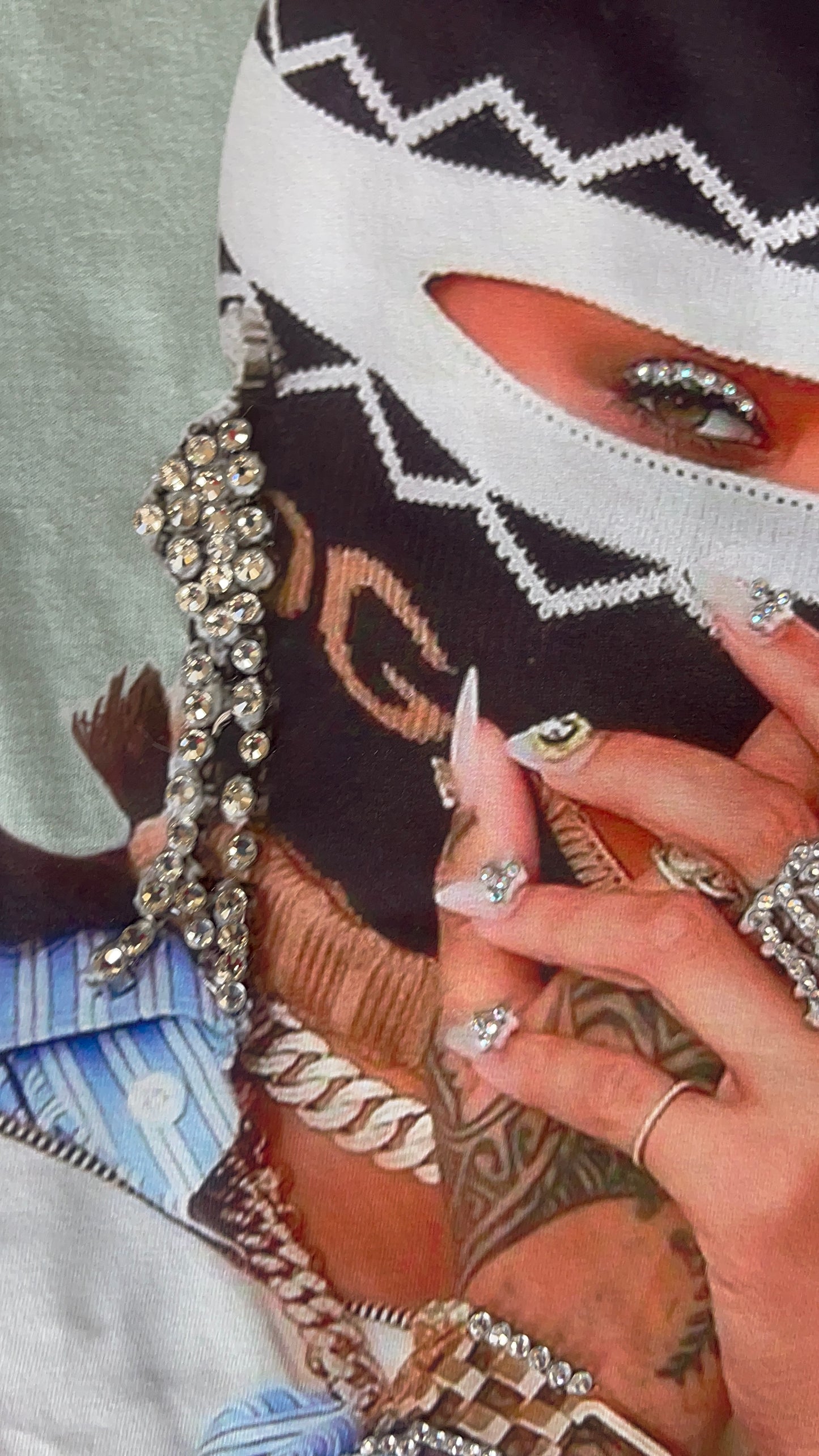 Rhinestone detail shot of jewelry, nails, and graphic on the seafoam green “Say Less” Tee.