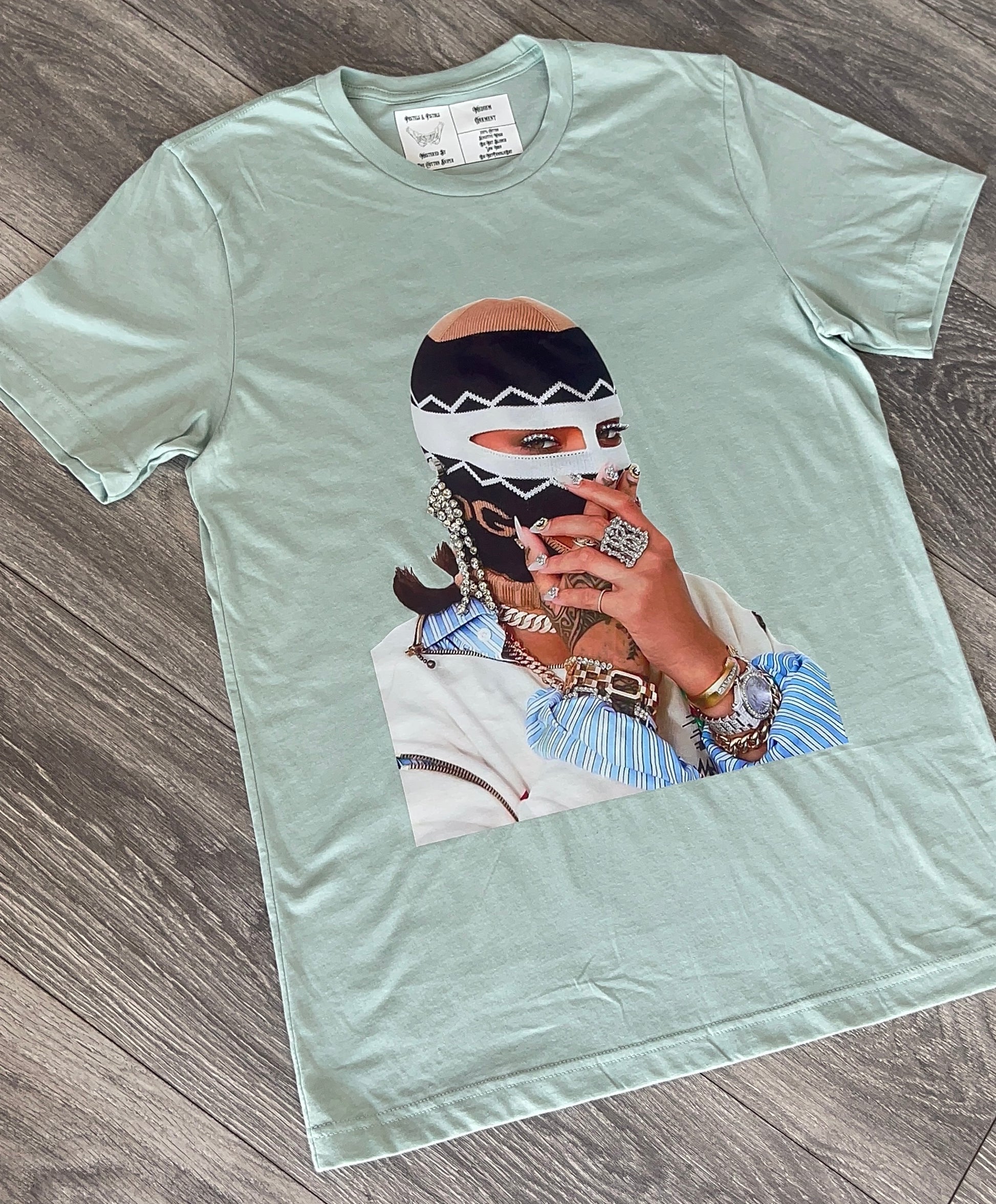 Seafoam green Pastels & Pistols “Say Less” Tee with rhinestone details displayed flat on wood floor.